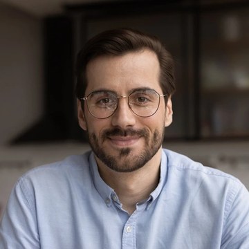Portrait of a smiling man in glasses, one of three review photographs published on the Nuvia checkout